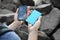 Woman charging smartphone with power bank on rocky mountain, closeup