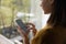 Woman chatting online on smartphone at window glass