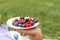 Woman in checkered stylish dress take berry from berries plate. Outdoor picnic