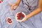 Woman in checkered stylish dress take berry from berries plate. Outdoor picnic