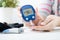 Woman checking blood sugar level by glucometer