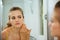 Woman checking her face in mirror in bathroom