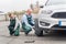 Woman checking how worker changing wheel of a car