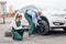 Woman checking how worker changing wheel of a car