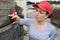 Woman checking tread on car tyre with gauge