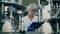 Woman checks bottles with milk on a industrial food and drinks plant conveyor.