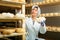 Woman cheesemaker checking aging process of cheese in maturing chamber