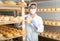 Woman cheesemaker in mask checking aging process of goat cheese