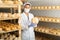 Woman cheesemaker in mask checking aging process of goat cheese