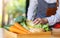 A woman chef holding and picking a fresh corn from a vegetables tray