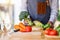 A woman chef holding and picking a fresh green broccoli from a vegetables tray