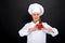 Woman chef make hand heart sign with tomato over dark background