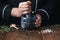 Woman chef pounding spices and herbs in mortar for food cooking on a black background