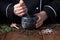 Woman chef pounding spices and herbs in mortar for food cooking on a black background