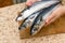 A woman chef slices a fish mackrel on a wooden Board