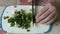 Woman chef slices fresh chives with a knife