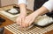 Woman chef wetting fingers to close sushi rolls