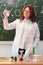 A woman chemistry teacher stands with white powder in a test tube near a painted blackboard. Teaching chemistry in a school class