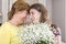 Woman and child with a bouquet of flowers in their house. Mother`s day