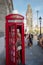 Woman and child exiting a red traditional telephone booth in Lon