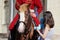 woman and child stroking a red horse on which the rider sits, dressed in period costume