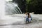 Woman and child walking around splashing fontain in the center o