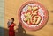 Woman in Chinese dress stand beside giant letter