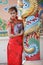 Woman in Chinese dress stand beside a pole