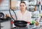 Woman is choosing new stewpot for her kitchen in tableware shop