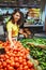 woman choosing red tomatoes from store shelf grocery shopping