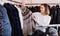 Woman choosing short coffee-colored fur jacket in women cloths store