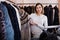 Woman choosing short coffee-colored fur jacket in women cloths store