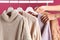 Woman choosing sweater on rack against color background