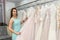Woman choosing white wedding dress in bride shop