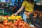 woman choosing yellow tomatoes from store shelf grocery shopping
