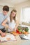 Woman chopping peppers with man reading cookbook