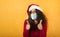 Woman with Christmas hat is optimistic about the defeat of covid 19 coronavirus. yellow background.