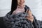 Woman with chunky knit blanket at home, closeup