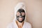 Woman in clay antiage moistening face mask is smiling. Good mood, positive self-love