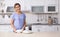 Woman with clean dishes near table in kitchen