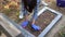 Woman is cleaning cemetery, washing black marble tombstone.