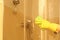 Woman cleaning door of shower cabin in bathroom