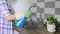 Woman cleaning double chrome sink in rubber gloves using spray and sponge