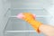 Woman cleaning empty refrigerator with rag