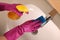 Woman cleaning faucet with sponge and detergent in bathroom, above view