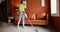 Woman cleaning floor with cordless vacuum cleaner at home