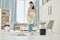 Woman cleaning the floor with a mop in the living room in home with a smile. Happy asian cleaner doing housework or job