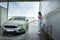 Woman cleaning her car with hose with spray foam and pressured water manual car washing from dirt