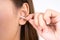 Woman cleaning her ear with a cotton swab. A woman suffered an infection after using the sticks incorrectly