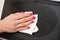 Woman cleaning laptop screen with white tissue, detail on her fingers holding paper towel